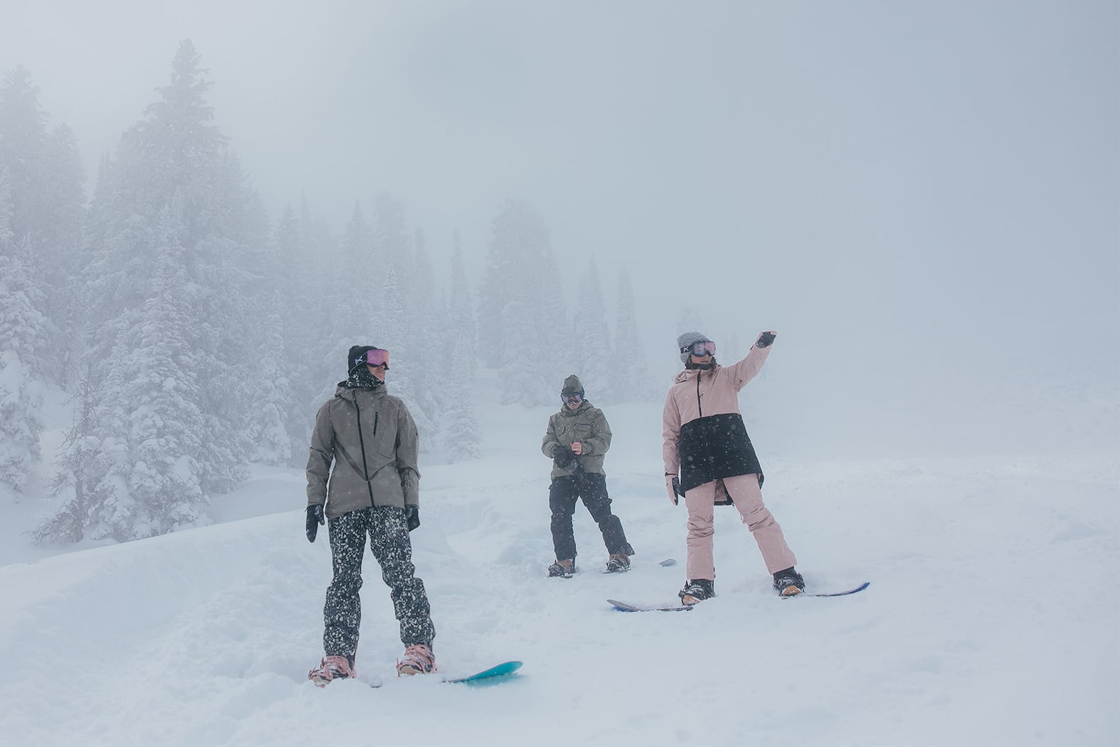 Burton DRYRIDE: A group of three snowboarders on a powder-covered ski trail with snow falling, deciding where to ride.