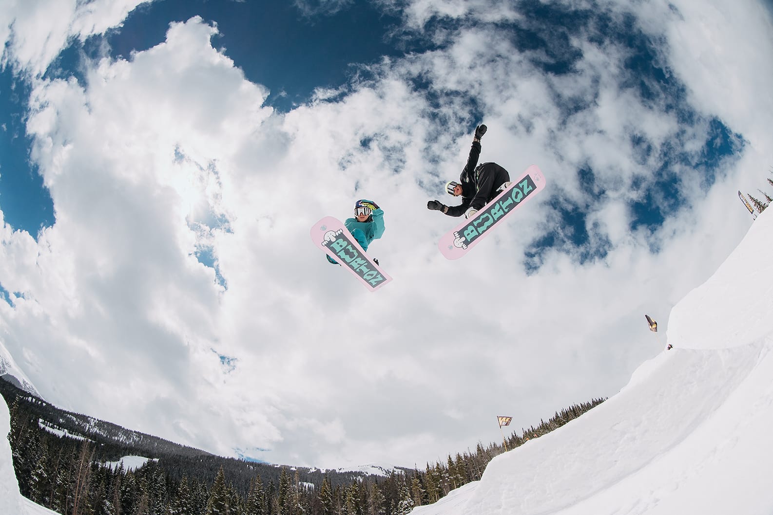 Goofy vs. Regular: Two riders getting massive air off a jump, viewed from below.