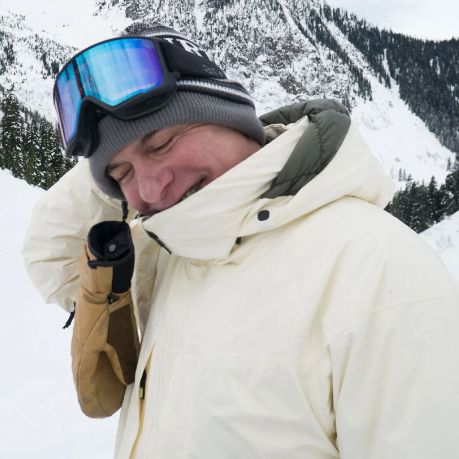 Person in winter clothing with goggles on a snowy mountain background