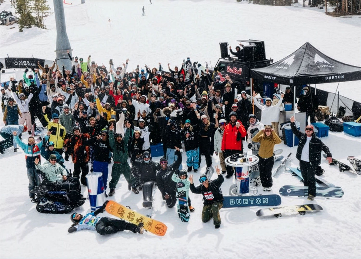 Large group of snowboarders gathered at the base for a photo