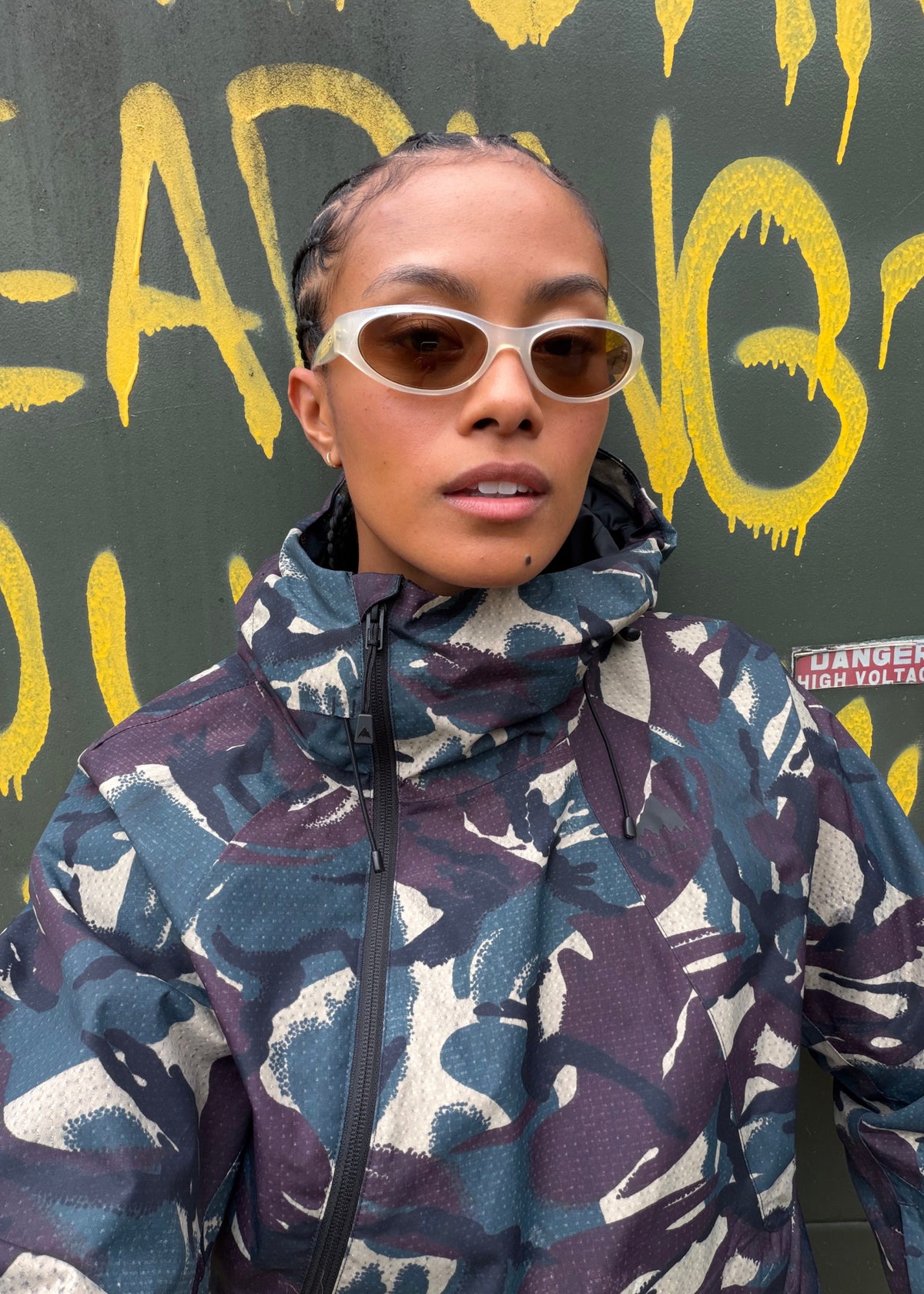 Women wearing sunglasses and a camouflage snowboarding jacket.
