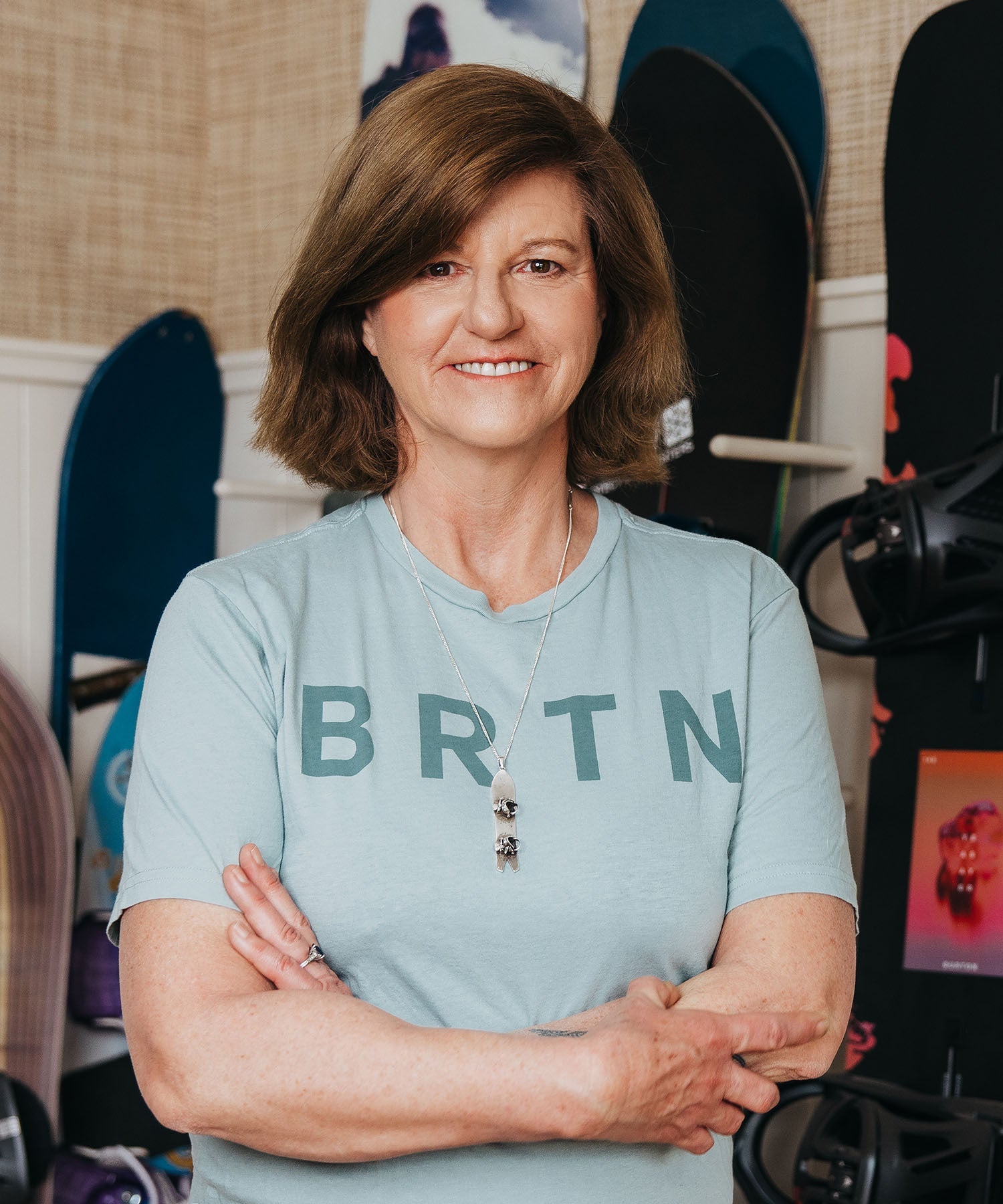 A photo of Donna Carpenter standing in front of snowboards leaning against the wall behind her.