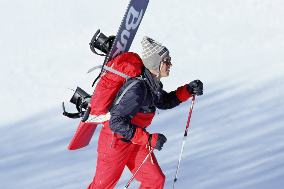 person walks uphill with an early prototype of a Burton hiking backpack with a board mounted