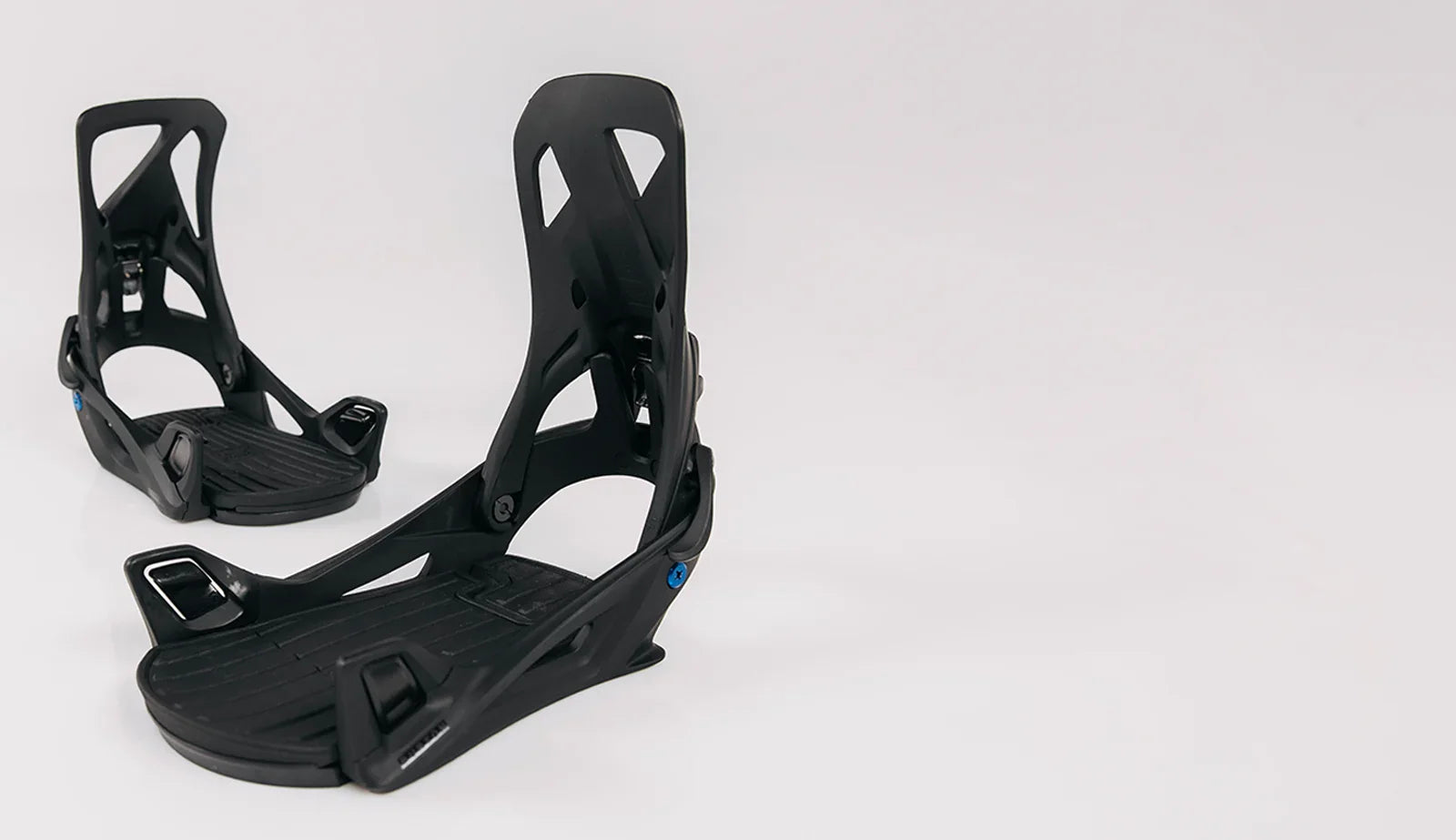 Black snowboard bindings on a white background