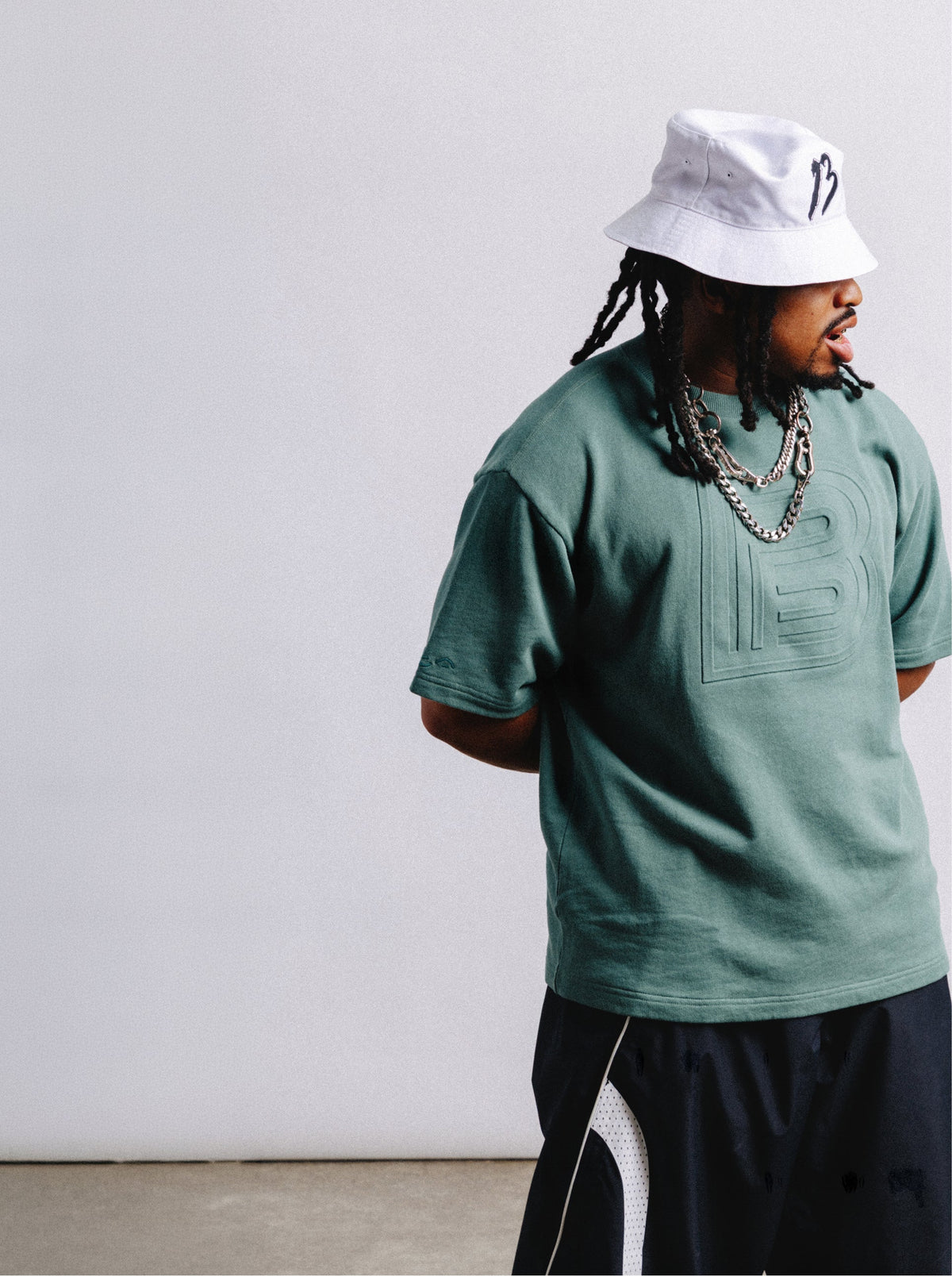 rider, zeb, modeling white Burton "B" bucket hat & embossed "B" tee in green