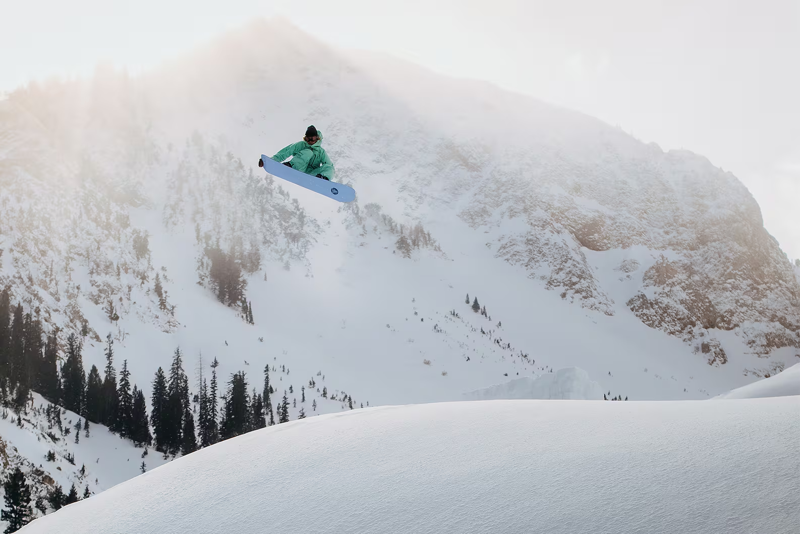A person snowboarding down a snowy mountain with trees in the background